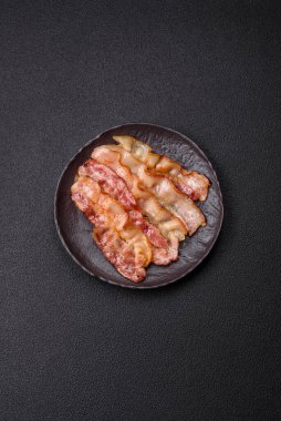 Tuz, baharat ve otlarla dilimlenmiş lezzetli pastırma koyu beton arka planda.