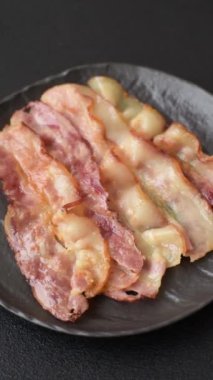 Tuz, baharat ve otlarla dilimlenmiş lezzetli pastırma koyu beton arka planda.