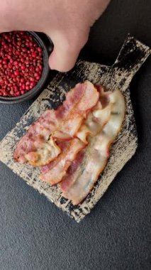 Tuz, baharat ve otlarla dilimlenmiş lezzetli pastırma koyu beton arka planda.