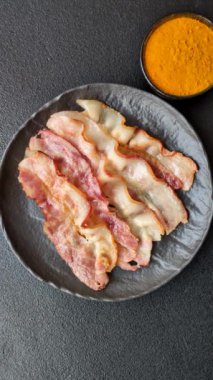 Tuz, baharat ve otlarla dilimlenmiş lezzetli pastırma koyu beton arka planda.