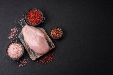 Koyu beton bir masada baharat ve otlarla taze tavuk filetosu. Et yemekleri için hazırlık.