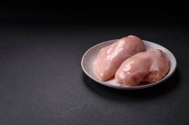 Koyu beton bir masada baharat ve otlarla taze tavuk filetosu. Et yemekleri için hazırlık.