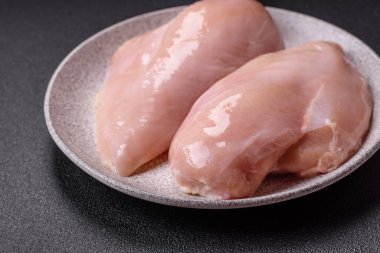 Koyu beton bir masada baharat ve otlarla taze tavuk filetosu. Et yemekleri için hazırlık.