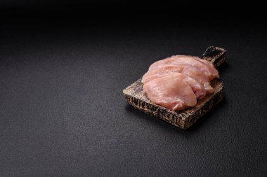 Koyu beton bir masada baharat ve otlarla taze tavuk filetosu. Et yemekleri için hazırlık.