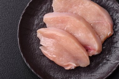 Koyu beton bir masada baharat ve otlarla taze tavuk filetosu. Et yemekleri için hazırlık.