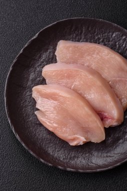 Koyu beton bir masada baharat ve otlarla taze tavuk filetosu. Et yemekleri için hazırlık.