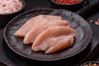 Koyu beton bir masada baharat ve otlarla taze tavuk filetosu. Et yemekleri için hazırlık.