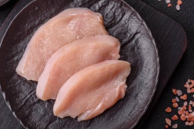 Koyu beton bir masada baharat ve otlarla taze tavuk filetosu. Et yemekleri için hazırlık.