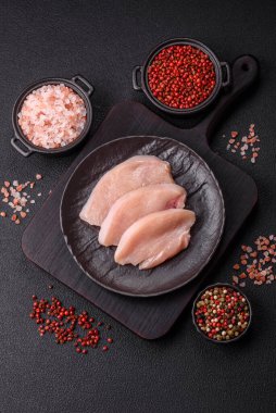 Koyu beton bir masada baharat ve otlarla taze tavuk filetosu. Et yemekleri için hazırlık.
