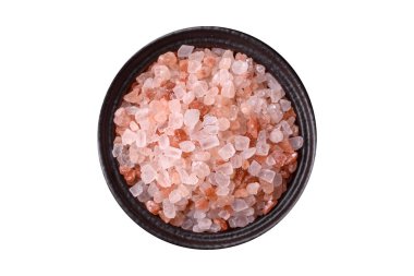 Beyaz arka planda siyah bir kasede pembe Himalaya tuzu. Mutfakta baharatlar ve katkı maddeleri var.