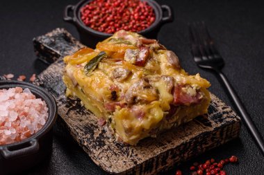 Koyu beton arka planda patates, et, sebze, tuz, baharat ve otlu çoban turtası.