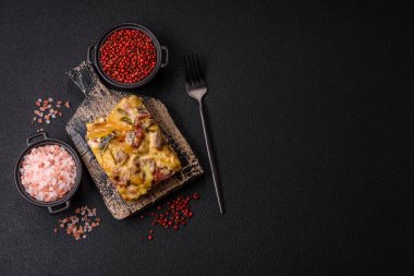 Koyu beton arka planda patates, et, sebze, tuz, baharat ve otlu çoban turtası.