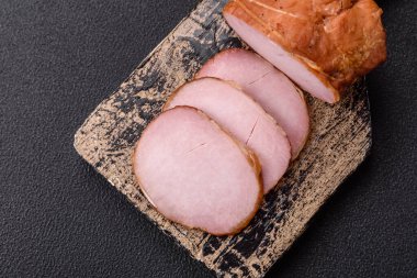 Et, tütsülenmiş, tuz, baharat ve otlarla dilimlenmiş koyu beton arka planda jambon.