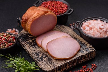 Et, tütsülenmiş, tuz, baharat ve otlarla dilimlenmiş koyu beton arka planda jambon.