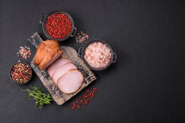 Et, tütsülenmiş, tuz, baharat ve otlarla dilimlenmiş koyu beton arka planda jambon.