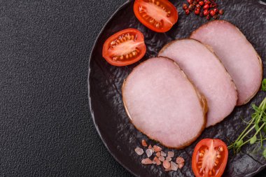 Et, tütsülenmiş, tuz, baharat ve otlarla dilimlenmiş koyu beton arka planda jambon.