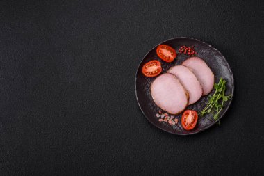 Et, tütsülenmiş, tuz, baharat ve otlarla dilimlenmiş koyu beton arka planda jambon.