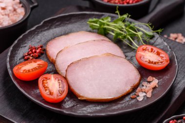 Et, tütsülenmiş, tuz, baharat ve otlarla dilimlenmiş koyu beton arka planda jambon.