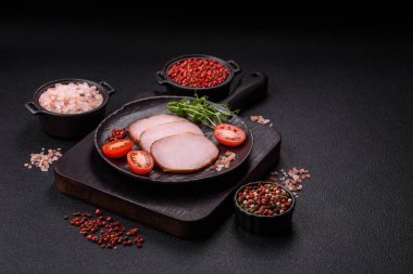Et, tütsülenmiş, tuz, baharat ve otlarla dilimlenmiş koyu beton arka planda jambon.