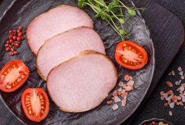 Et, tütsülenmiş, tuz, baharat ve otlarla dilimlenmiş koyu beton arka planda jambon.