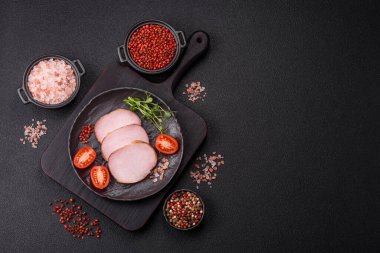 Et, tütsülenmiş, tuz, baharat ve otlarla dilimlenmiş koyu beton arka planda jambon.