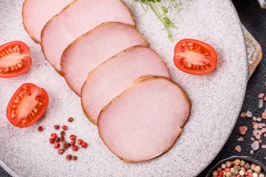 Et, tütsülenmiş, tuz, baharat ve otlarla dilimlenmiş koyu beton arka planda jambon.