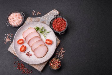 Et, tütsülenmiş, tuz, baharat ve otlarla dilimlenmiş koyu beton arka planda jambon.