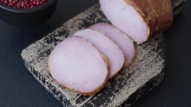 Et, tütsülenmiş, tuz, baharat ve otlarla dilimlenmiş koyu beton arka planda jambon.