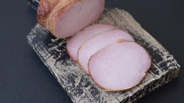 Et, tütsülenmiş, tuz, baharat ve otlarla dilimlenmiş koyu beton arka planda jambon.
