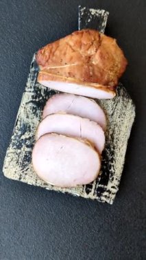 Et, tütsülenmiş, tuz, baharat ve otlarla dilimlenmiş koyu beton arka planda jambon.