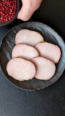 Et, tütsülenmiş, tuz, baharat ve otlarla dilimlenmiş koyu beton arka planda jambon.