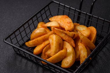 Koyu arkaplanda peynirli ve otlu fırında patates dilimleri. Ev yapımı organik sebze vejetaryen patates dilimleri.