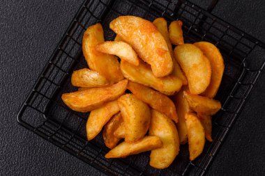 Koyu arkaplanda peynirli ve otlu fırında patates dilimleri. Ev yapımı organik sebze vejetaryen patates dilimleri.