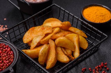 Koyu arkaplanda peynirli ve otlu fırında patates dilimleri. Ev yapımı organik sebze vejetaryen patates dilimleri.