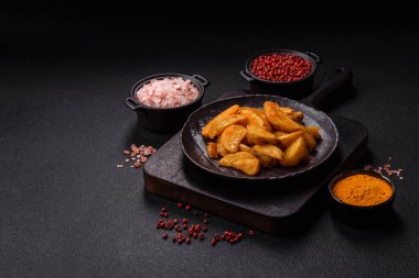 Koyu arkaplanda peynirli ve otlu fırında patates dilimleri. Ev yapımı organik sebze vejetaryen patates dilimleri.