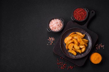 Koyu arkaplanda peynirli ve otlu fırında patates dilimleri. Ev yapımı organik sebze vejetaryen patates dilimleri.