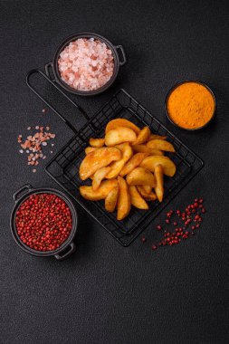 Koyu arkaplanda peynirli ve otlu fırında patates dilimleri. Ev yapımı organik sebze vejetaryen patates dilimleri.