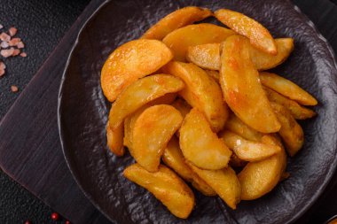 Koyu arkaplanda peynirli ve otlu fırında patates dilimleri. Ev yapımı organik sebze vejetaryen patates dilimleri.