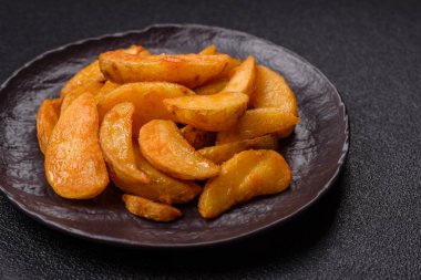 Koyu arkaplanda peynirli ve otlu fırında patates dilimleri. Ev yapımı organik sebze vejetaryen patates dilimleri.