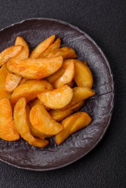 Koyu arkaplanda peynirli ve otlu fırında patates dilimleri. Ev yapımı organik sebze vejetaryen patates dilimleri.