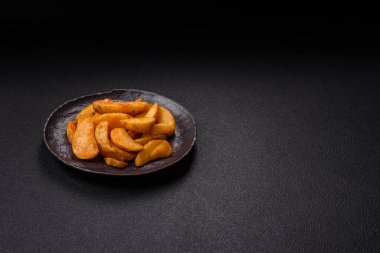 Koyu arkaplanda peynirli ve otlu fırında patates dilimleri. Ev yapımı organik sebze vejetaryen patates dilimleri.