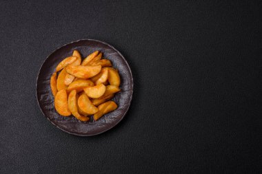 Koyu arkaplanda peynirli ve otlu fırında patates dilimleri. Ev yapımı organik sebze vejetaryen patates dilimleri.