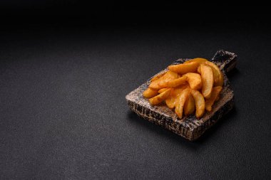 Koyu arkaplanda peynirli ve otlu fırında patates dilimleri. Ev yapımı organik sebze vejetaryen patates dilimleri.