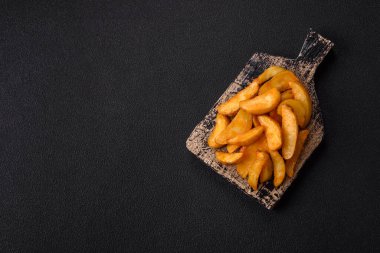 Koyu arkaplanda peynirli ve otlu fırında patates dilimleri. Ev yapımı organik sebze vejetaryen patates dilimleri.