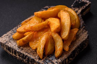 Koyu arkaplanda peynirli ve otlu fırında patates dilimleri. Ev yapımı organik sebze vejetaryen patates dilimleri.