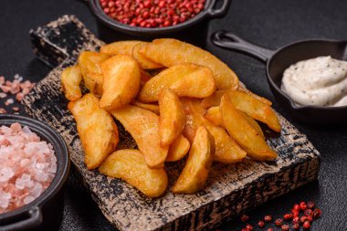 Koyu arkaplanda peynirli ve otlu fırında patates dilimleri. Ev yapımı organik sebze vejetaryen patates dilimleri.