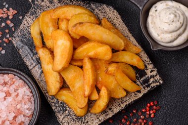 Koyu arkaplanda peynirli ve otlu fırında patates dilimleri. Ev yapımı organik sebze vejetaryen patates dilimleri.