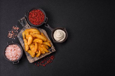 Koyu arkaplanda peynirli ve otlu fırında patates dilimleri. Ev yapımı organik sebze vejetaryen patates dilimleri.