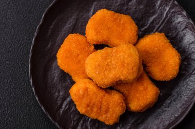 Delicious fresh crispy chicken nuggets on a dark concrete background. Unhealthy food, fast food