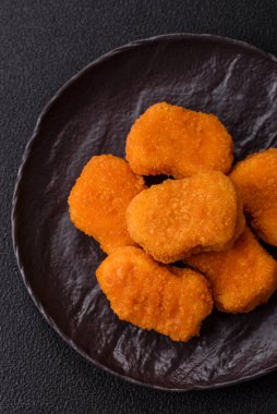 Delicious fresh crispy chicken nuggets on a dark concrete background. Unhealthy food, fast food